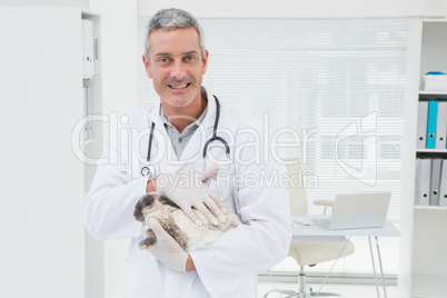 Smiling vet with a rabbit in his arms