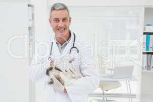 Smiling vet with a rabbit in his arms