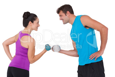 Fit man and woman lifting dumbbells