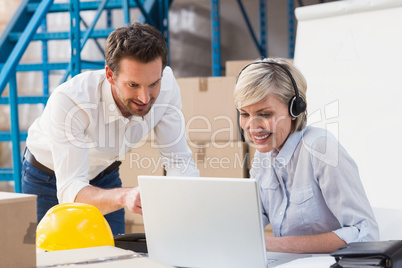 Warehouse managers using laptop and wearing headset Warehouse managers using laptop and wearing headset