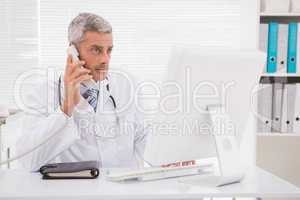 Doctor phoning and using computer