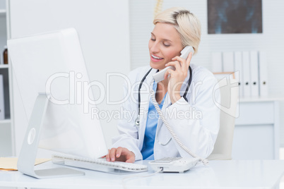 Doctor on call while using computer in clinic