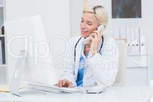 Doctor on call while using computer in clinic
