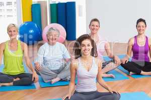 Class practicing yoga with instructor at gym