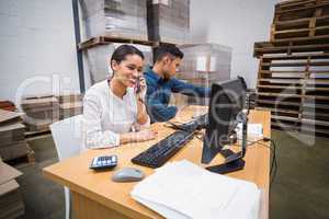 Warehouse managers using telephone and laptop