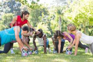 Fitness group planking in park with coach