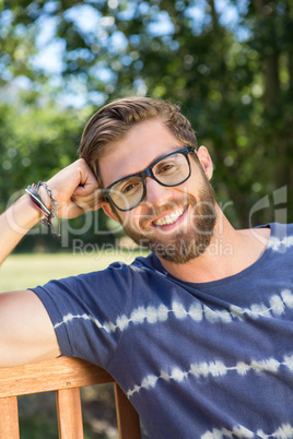 Handsome hipster sitting on park bench