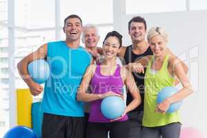 Cheerful people with medicine balls in fitness studio