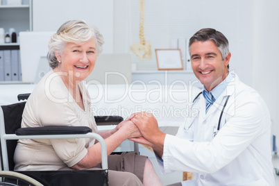 Happy doctor holding senior patients hands