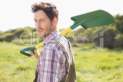 Happy farmer carrying his shovel