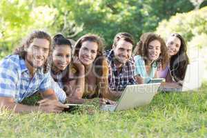 Smiling friends in the park using tablet pc and laptop