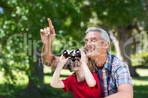 Happy little boy using binoculars with his father