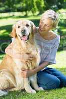 Happy blonde hugging her dog in the park