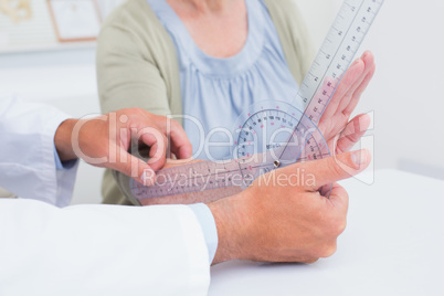 Physiotherapist examining patients wrist with goniometer