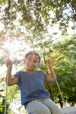 Happy little girl on a swing in the park