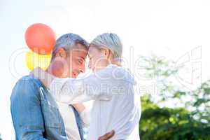 Cute couple hugging and holding balloons at the park