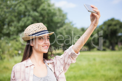 Pretty brunette taking a selfie in park