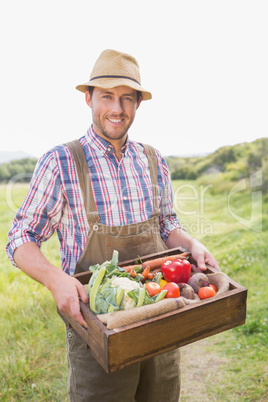 Happy farmer carrying box of veg