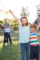 Happy siblings holding balloons at the park