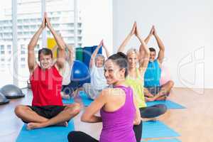 Instructor with class practicing yoga in fitness studio