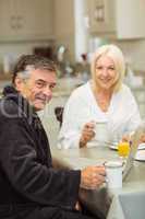 Mature couple having breakfast together man using laptop