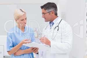 Doctor and nurse discussing over notes in clinic