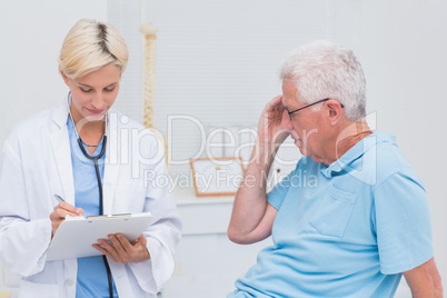 Doctor writing prescription for senior patient