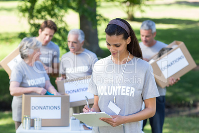 Smiling volunteer brunette writing on cipboard