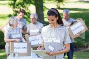 Smiling volunteer brunette writing on cipboard