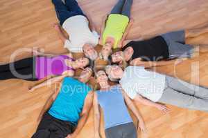 People lying in circle on hardwood floor at gym