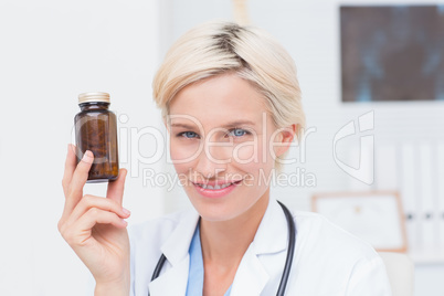 Confident female doctor holding medicine bottle