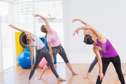 Trainer and female friends doing stretching exercise