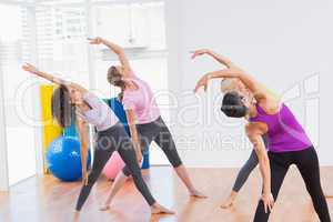 Trainer and female friends doing stretching exercise