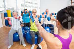 Instructor with class lifting dumbbells