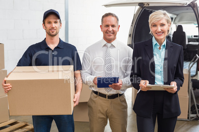 Warehouse managers and delivery driver smiling at camera