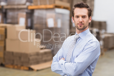 Serious manager with arms crossed in warehouse