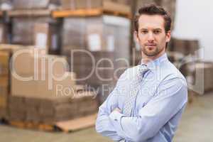 Serious manager with arms crossed in warehouse