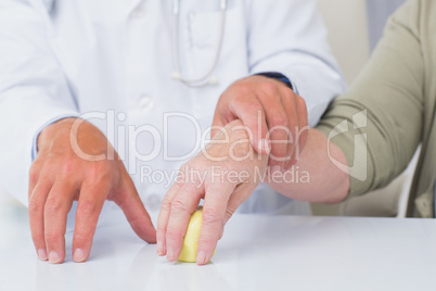 Doctor assisting female patient to hold weight at table