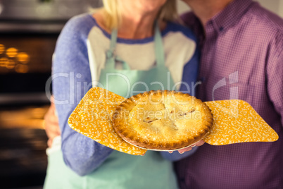 Mature blonde holding fresh pie with husband kissing her