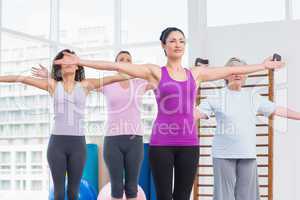 Friends with arms outstretched exercising in gym