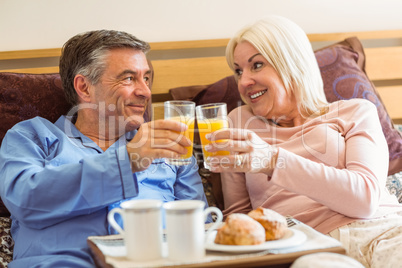 Happy mature couple having breakfast in bed