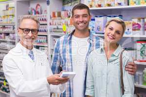 Pharmacist and costumers smiling looking at camera