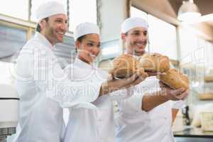 Smiling colleagues showing loaf of bread