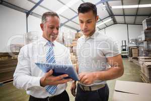 Warehouse manager using tablet pc with colleague