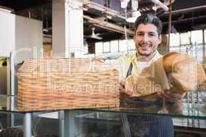 Smiling server in apron offering a bread