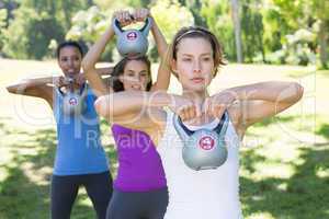 Fitness group working out in park with kettle bells