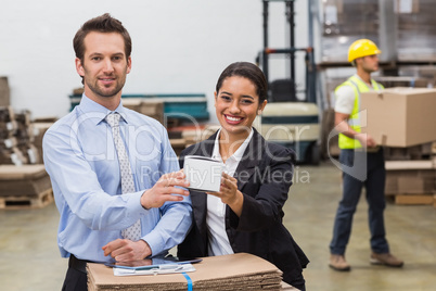 Warehouse managers showing box to camera