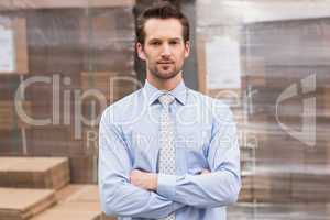 Serious manager with arms crossed in warehouse