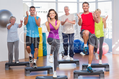 People performing step aerobics exercise in gym