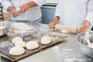 Co-workers kneading uncooked dough together